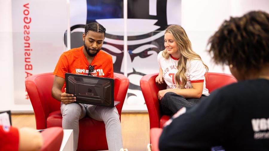 Students looking at a laptop in the College of Business lounge