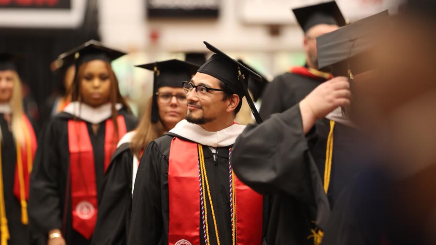 Student looking into the crowd as they walk in commencement